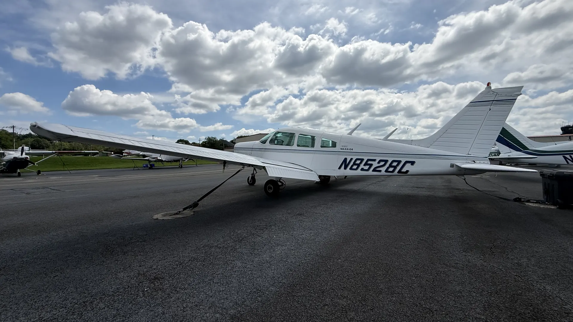 The Warrior from behind the left wing, tail and fuselage against a broken cloud deck.